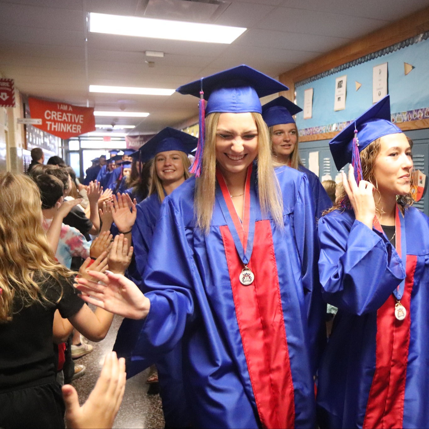 graduates high five students in hallway