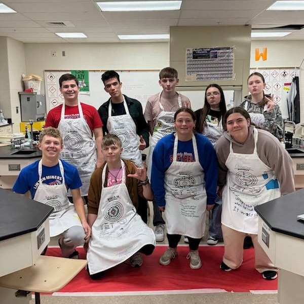 students model aprons they decorated in chemistry lab