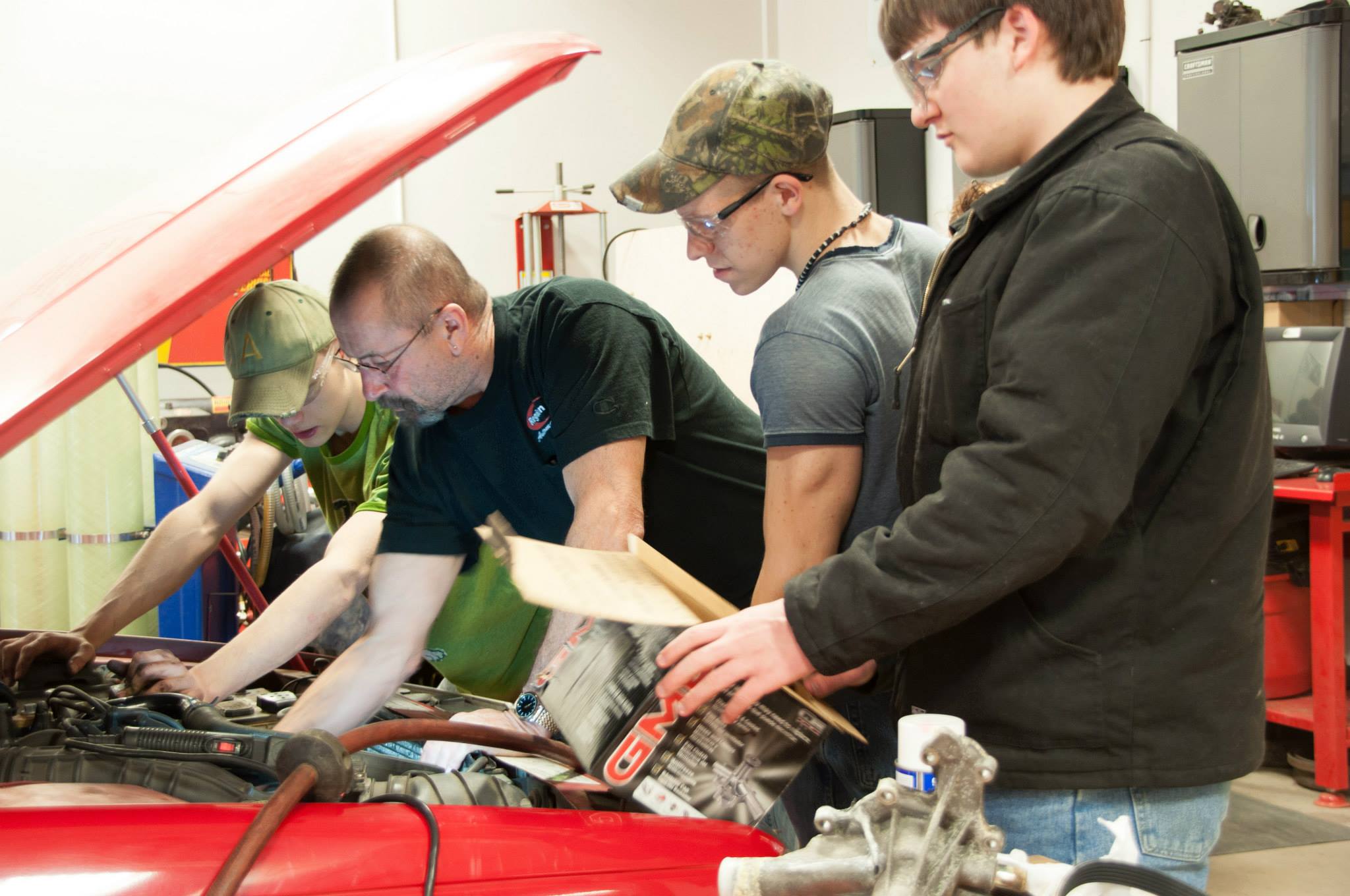 Group of students work on car engine