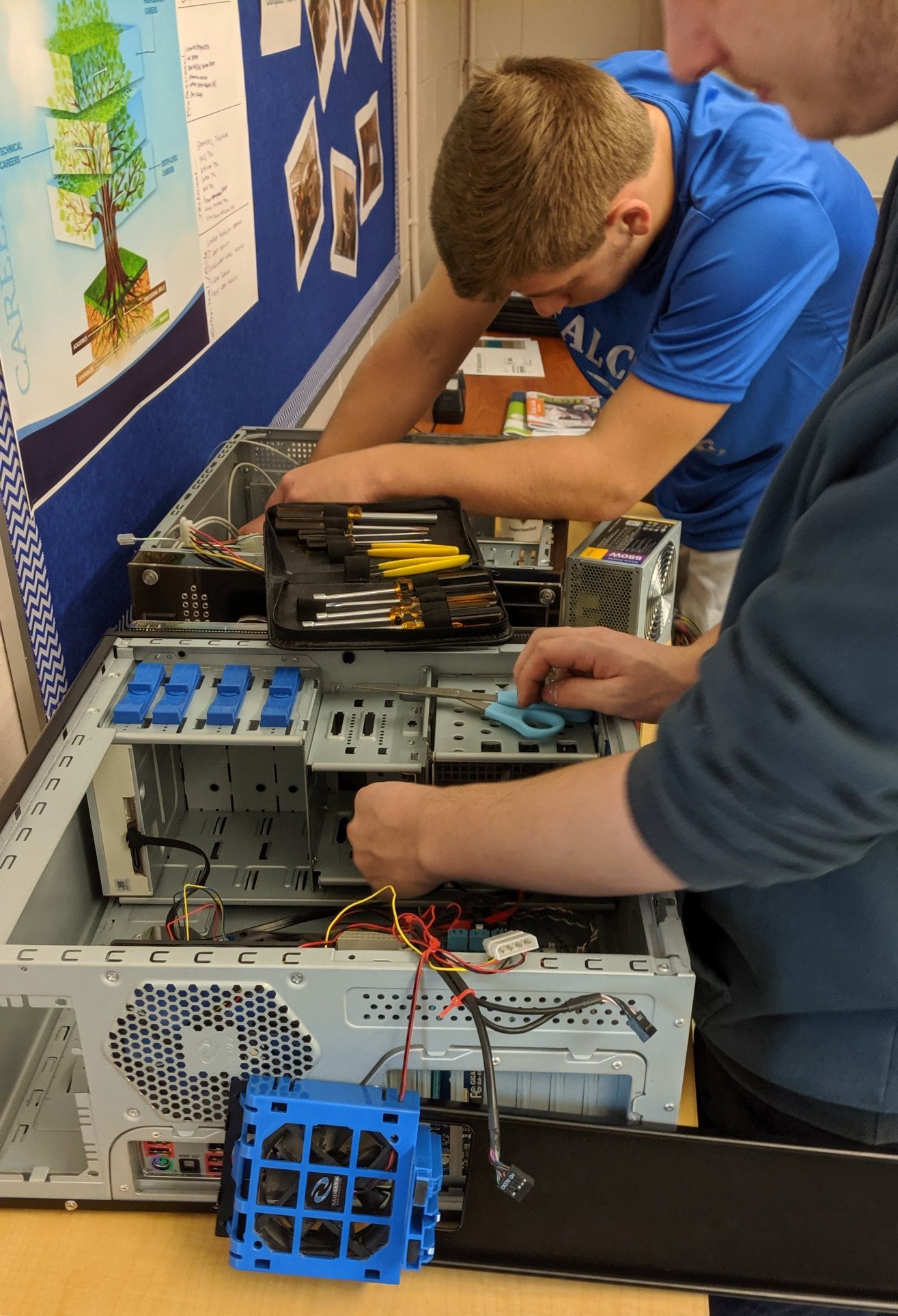 Two students install hardware into a computer