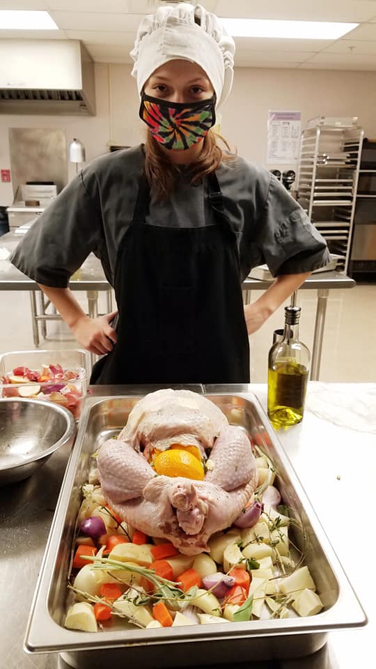 Student proudly poses with Thanksgiving turkey and vegetables