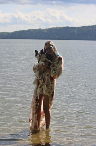 Taylor standing by a lake holding her dog.