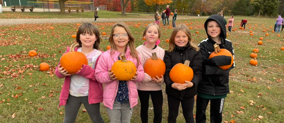 Students standing holding pumpkins