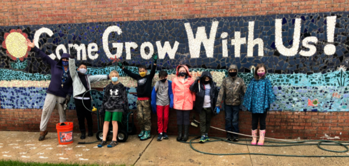 students and teacher posing in front of mural that says "Come Grow With Us!"