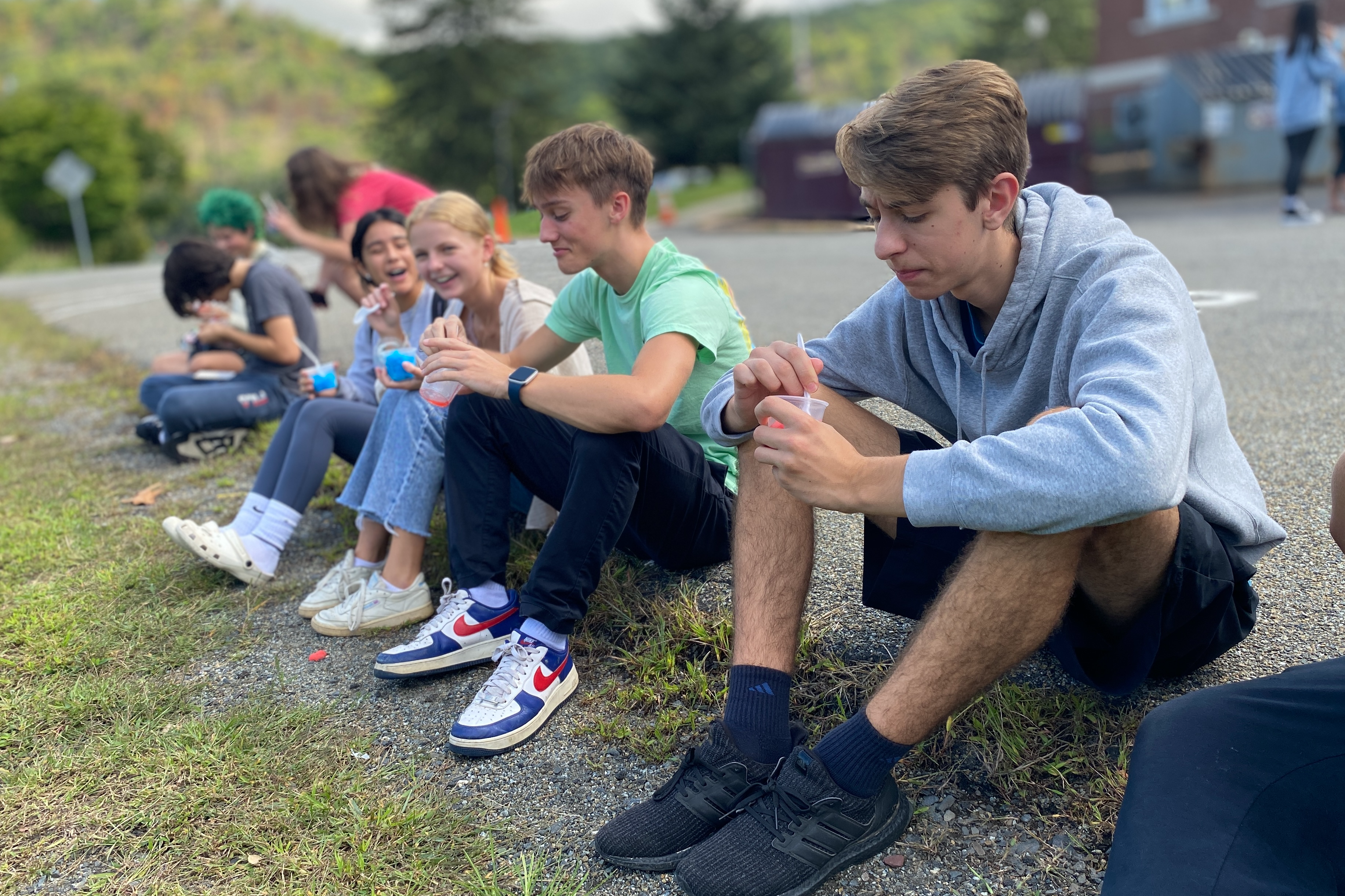 High School Students sitting on grass eating italian ices
