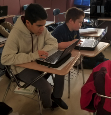 A photo of two students working in their laptops.