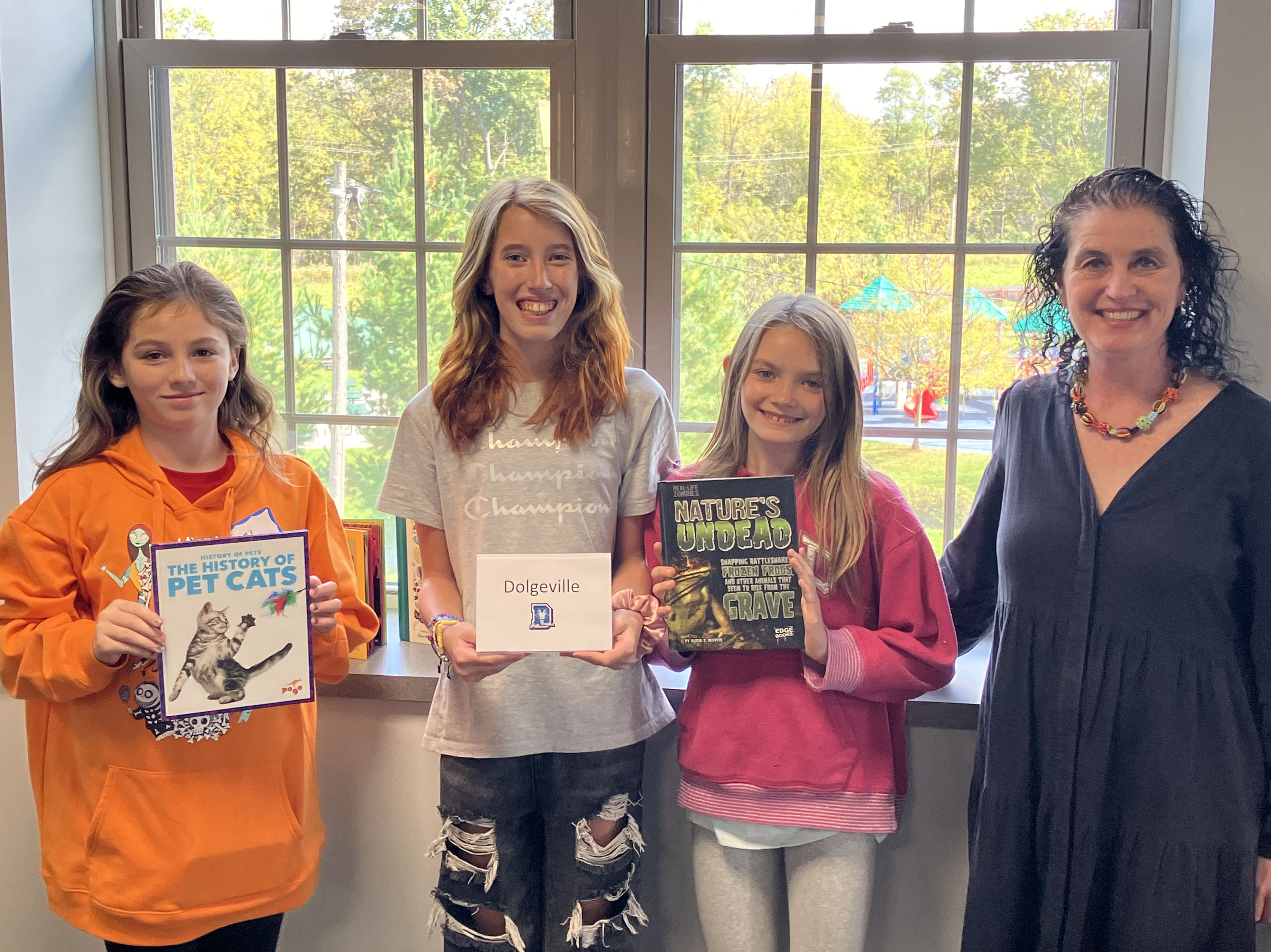 Honors Program students posing with books and author in front of windows