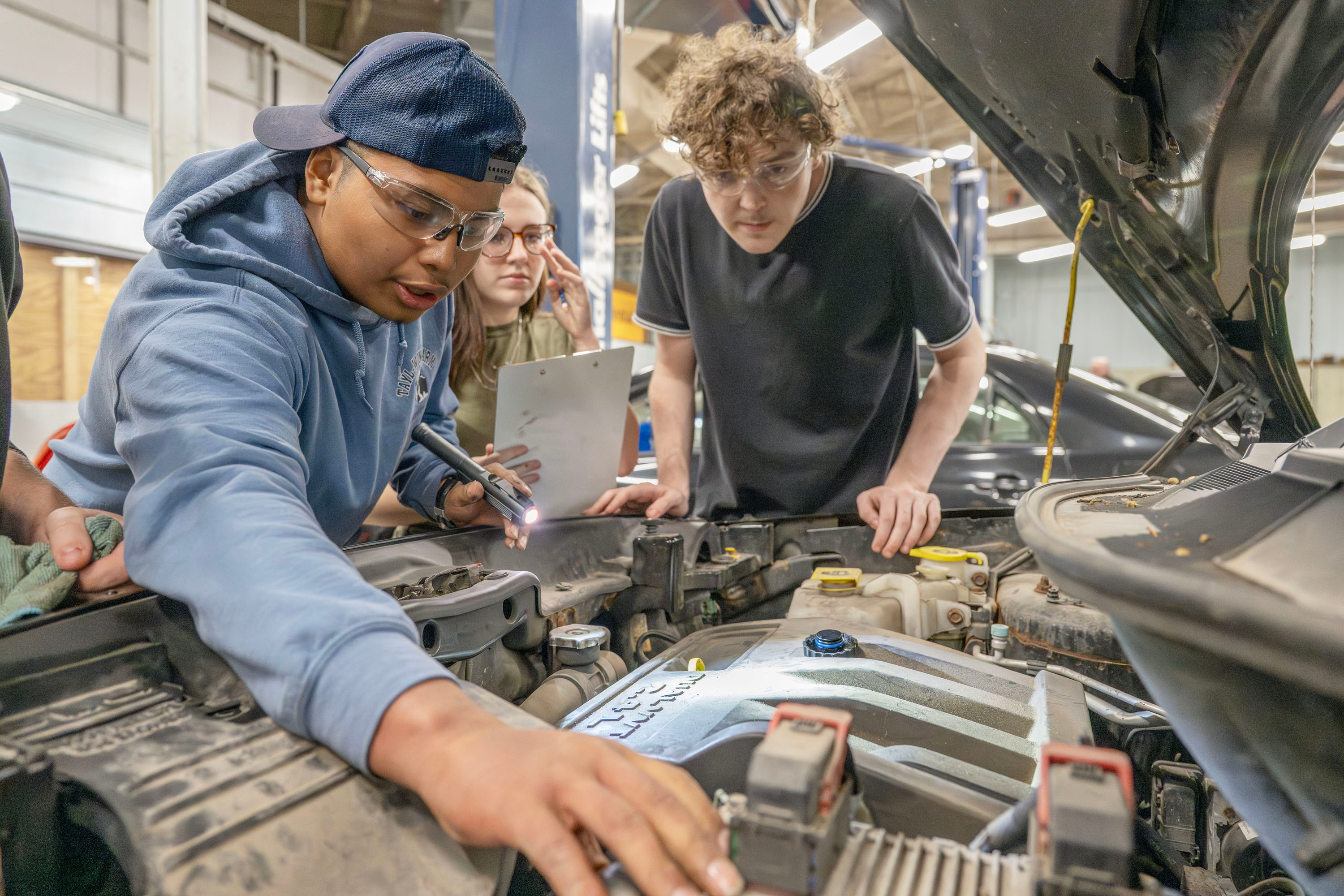 Three Automotive Technology students working on a car