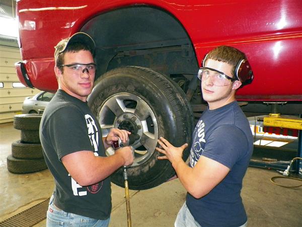 Two Automotive Technology students working on a car