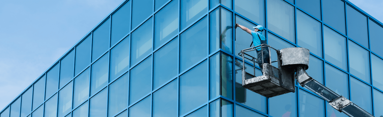 man cleaning the window outside of an office building