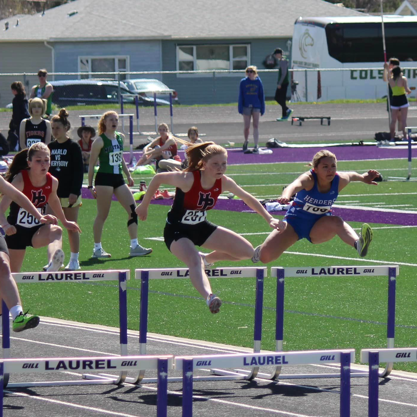 female track athlete jumping over a hurdle
