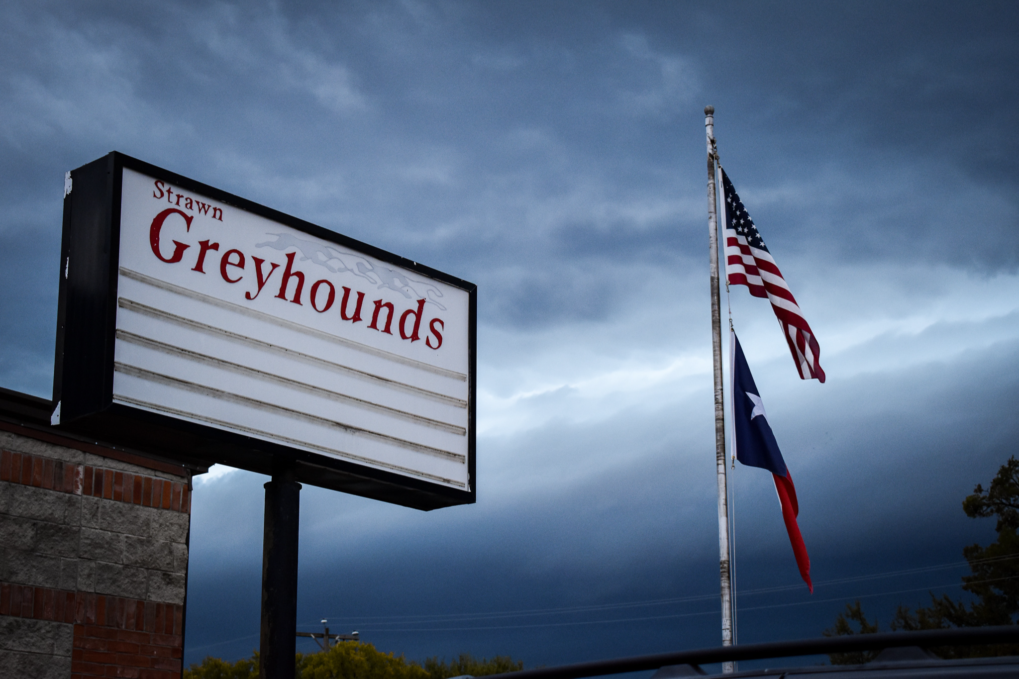 Strawn Greyhounds sign with US & Texas flags, storm in background
