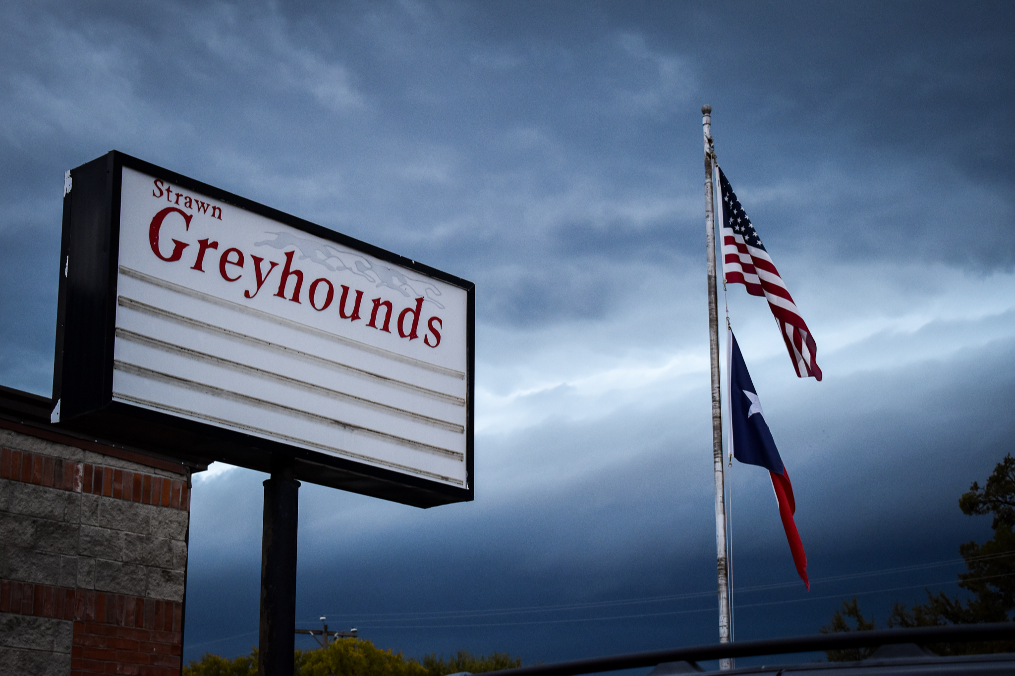 Strawn Greyhounds sign with US & Texas flags, storm in background. Photo by Hayden Nowak