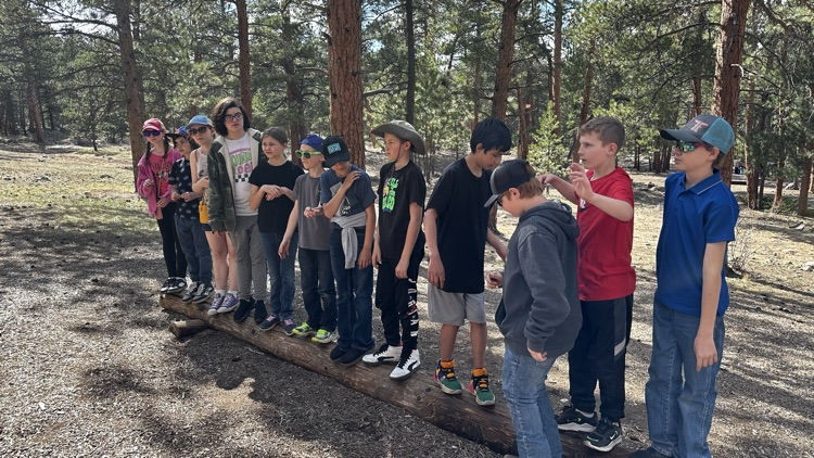 group of students standing on a log outside