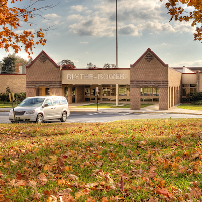 A white van parked in front of a building named "Brytle-Bowlen" with autumn leaves on the ground.