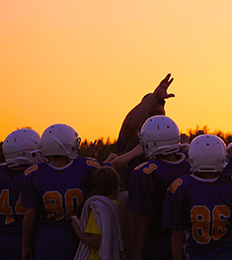 Football players standing in front of a sunset