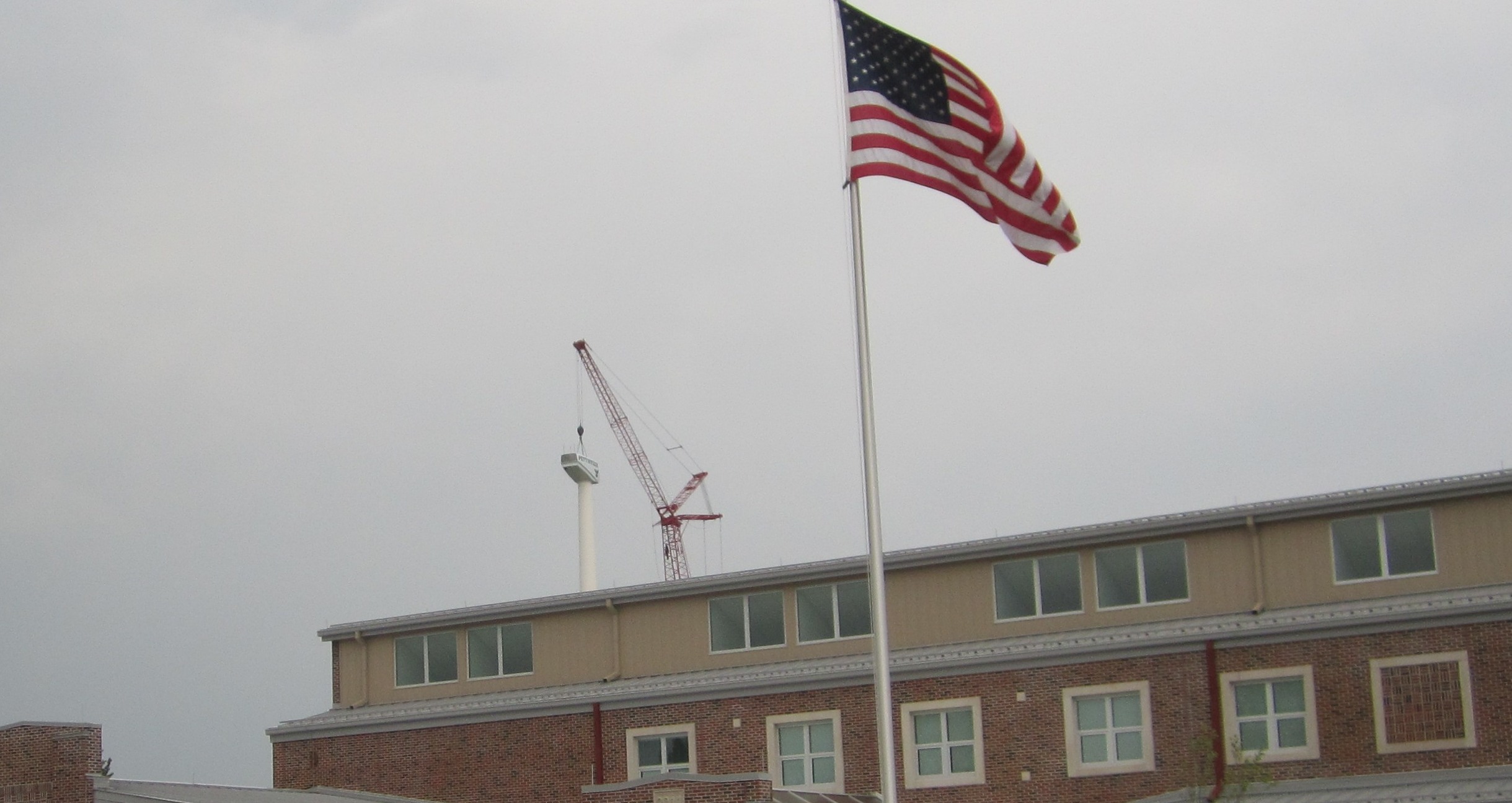 A picture of the side of the school with the flag pole in the front being the main focus