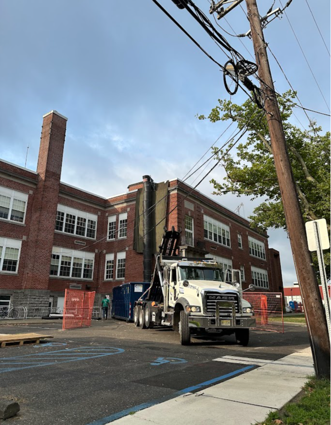 new dumpster being delivered to phs for roof removal