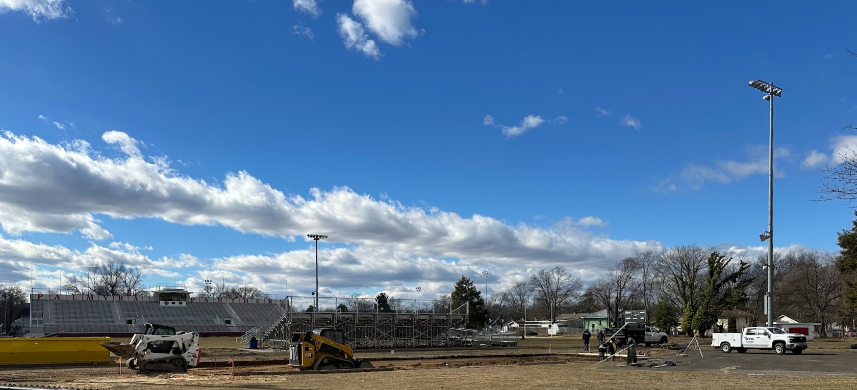 wide shot of construction happening behind visitor stands at Matt Curtis Stadium