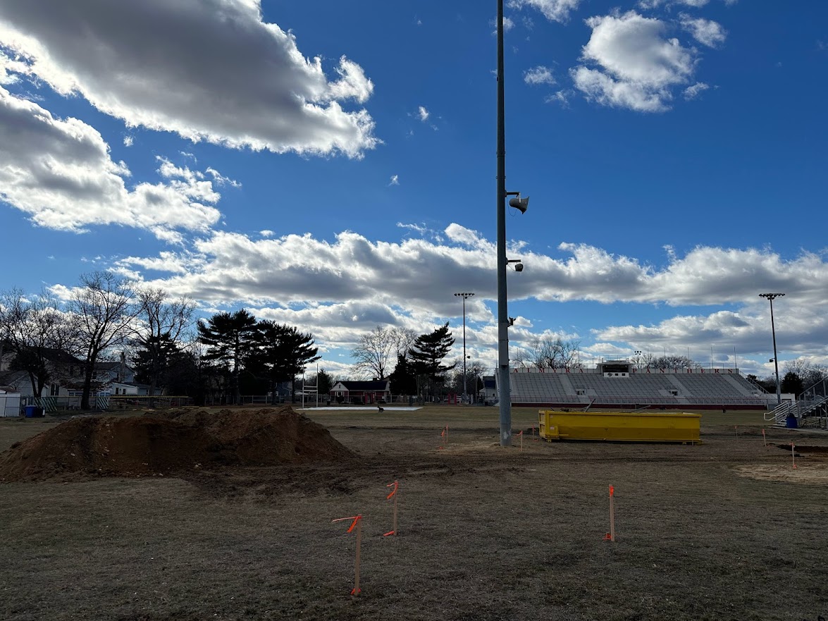 wide shot of construction happening behind visitor stands at Matt Curtis Stadium