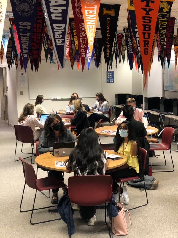 classroom with students & ceiling filled with pennants from various colleges hanging down