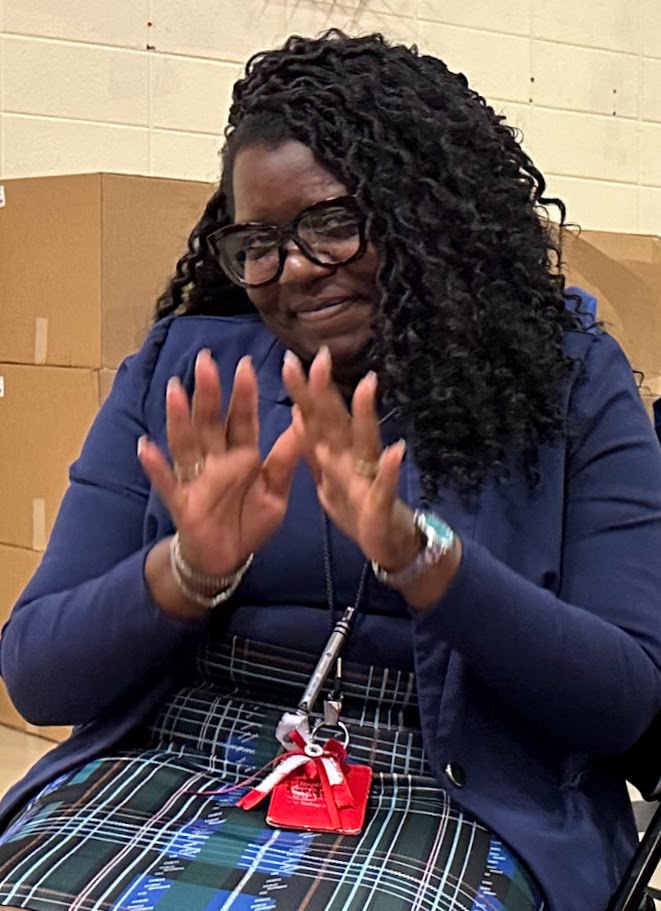 Principal Lee smiling in the audience of a meeting