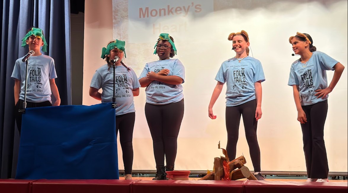 5 students on stage in blue shirts and animal hats