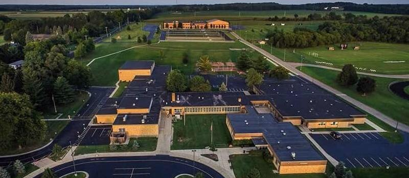Overview image of the high school building with trees and parking lot included