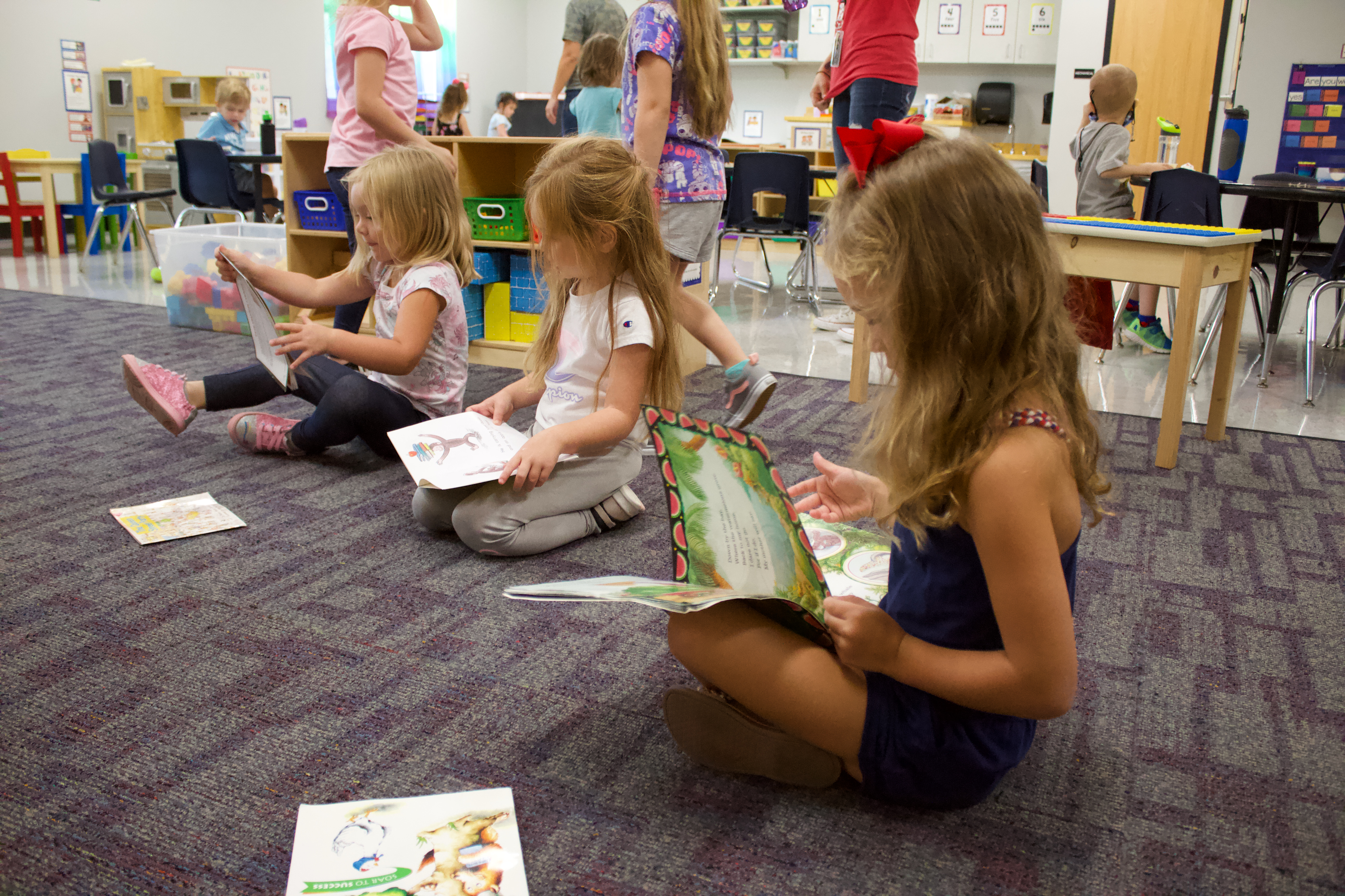 Preschool students sitting on the floor looking at picture books