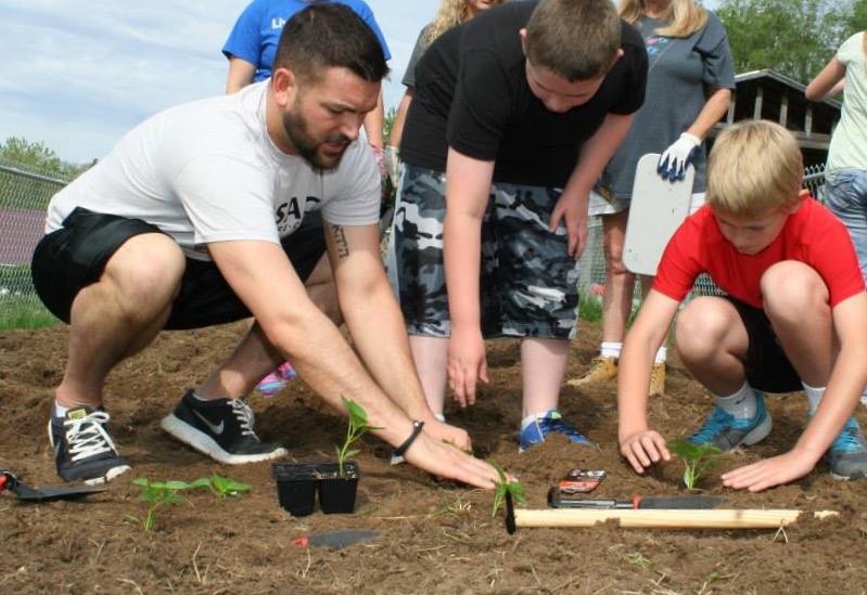 Man helping students plant things