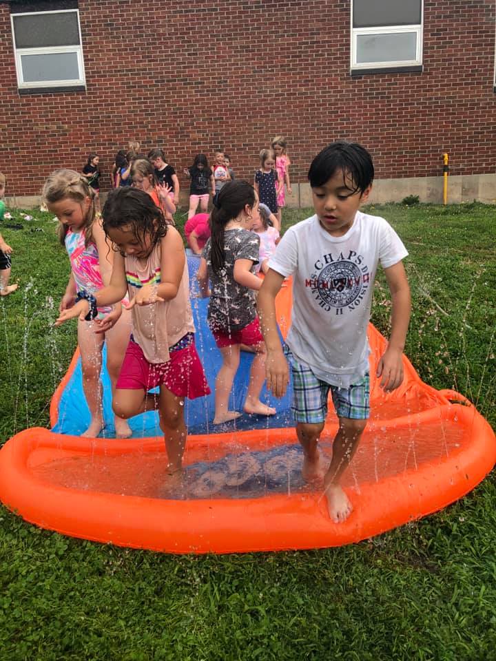 students run through water on an orange slip and slide
