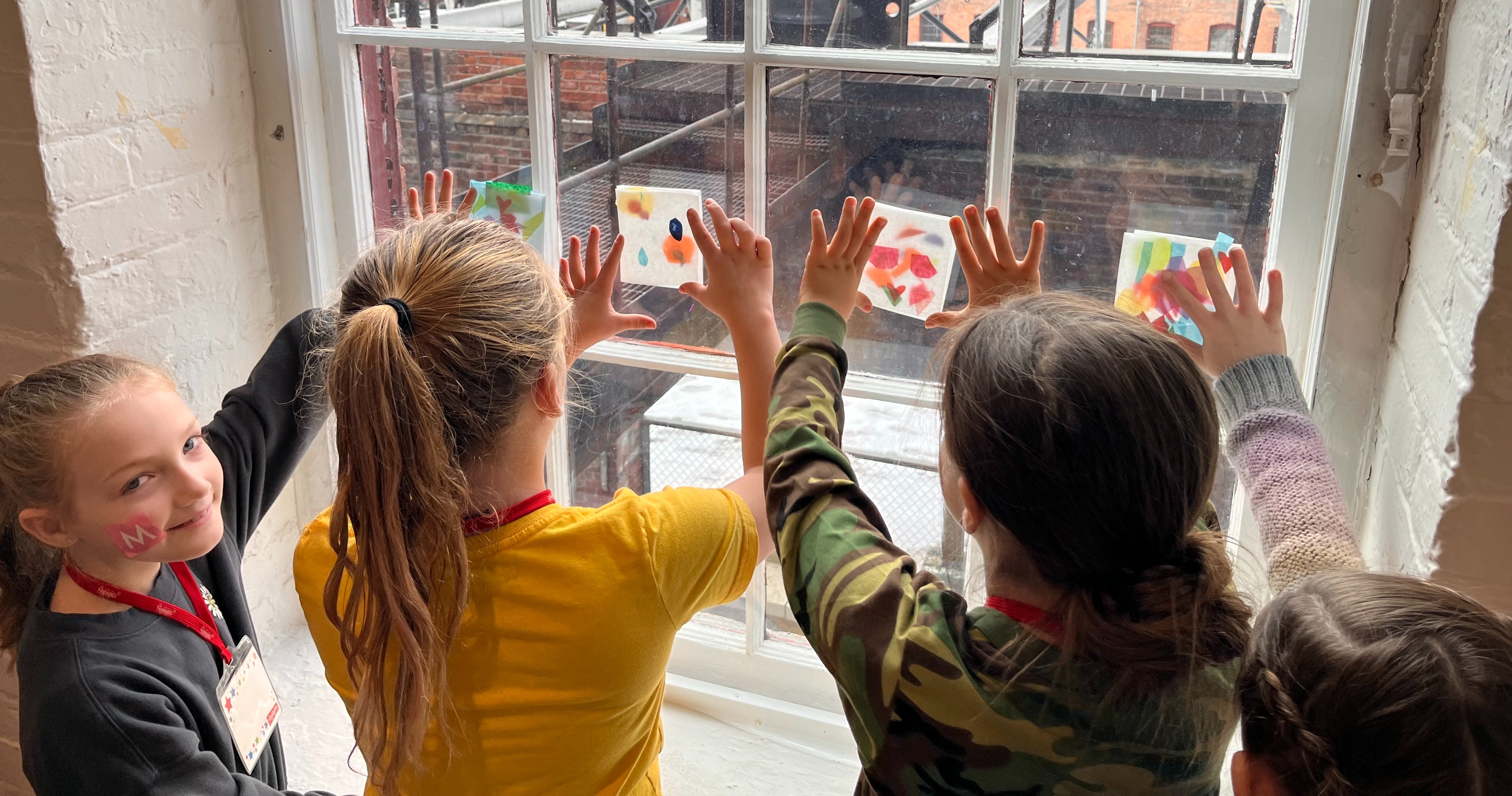 Students holding transparent art to windows at MASS MoCA