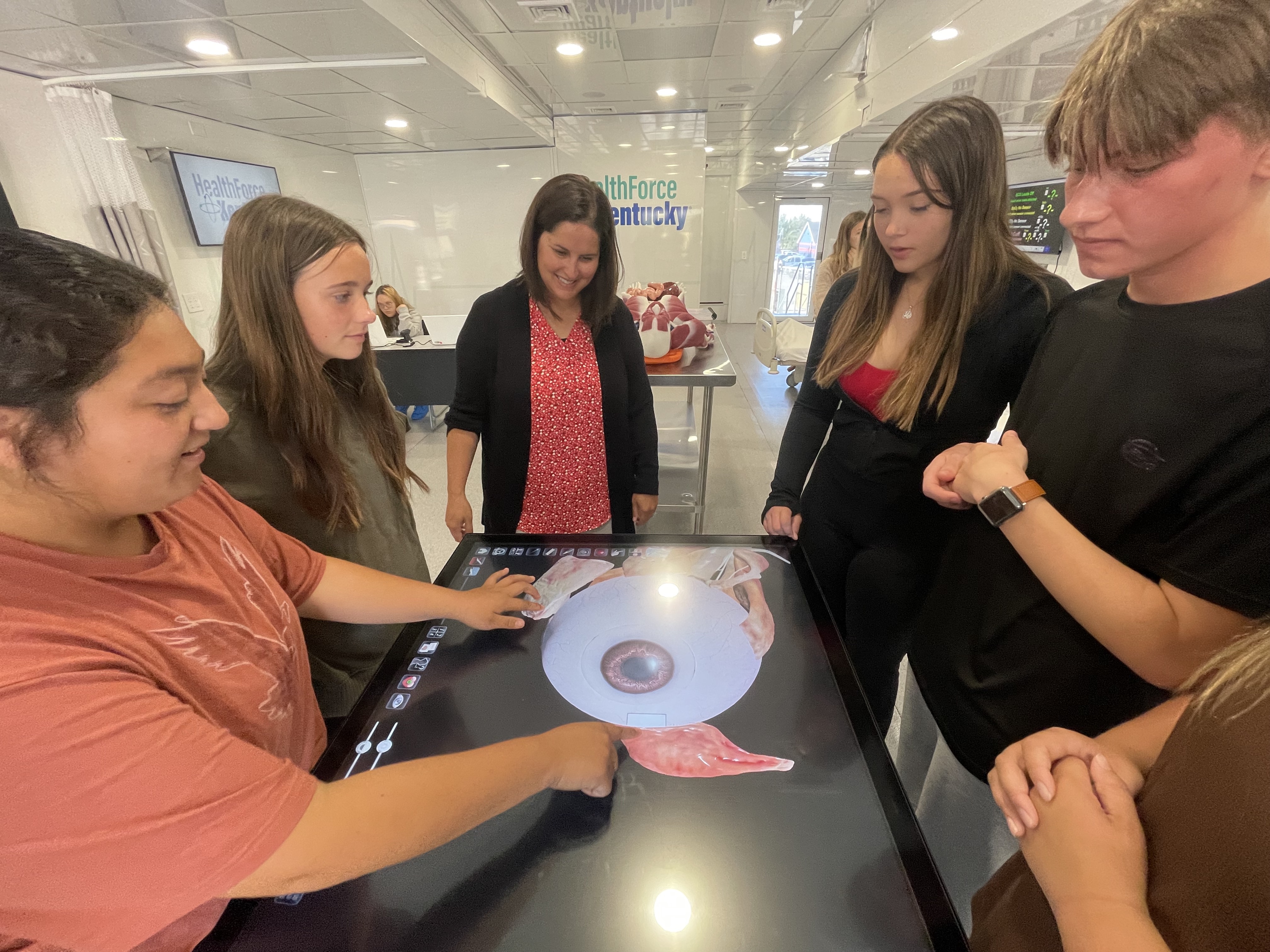 Students gathered around a large screen showing a human eye