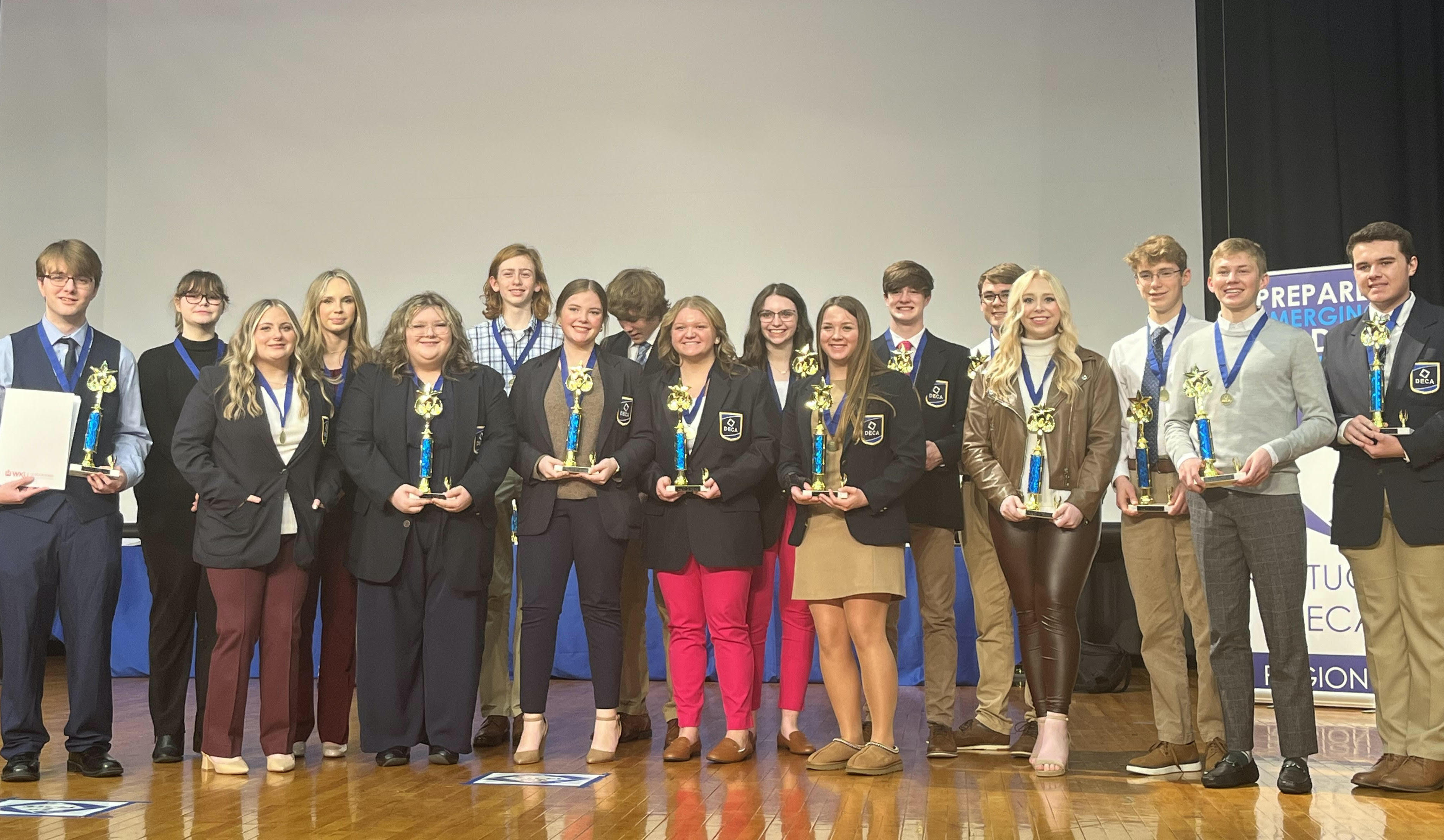 GCHS DECA Region 2 award winners on stage with trophies