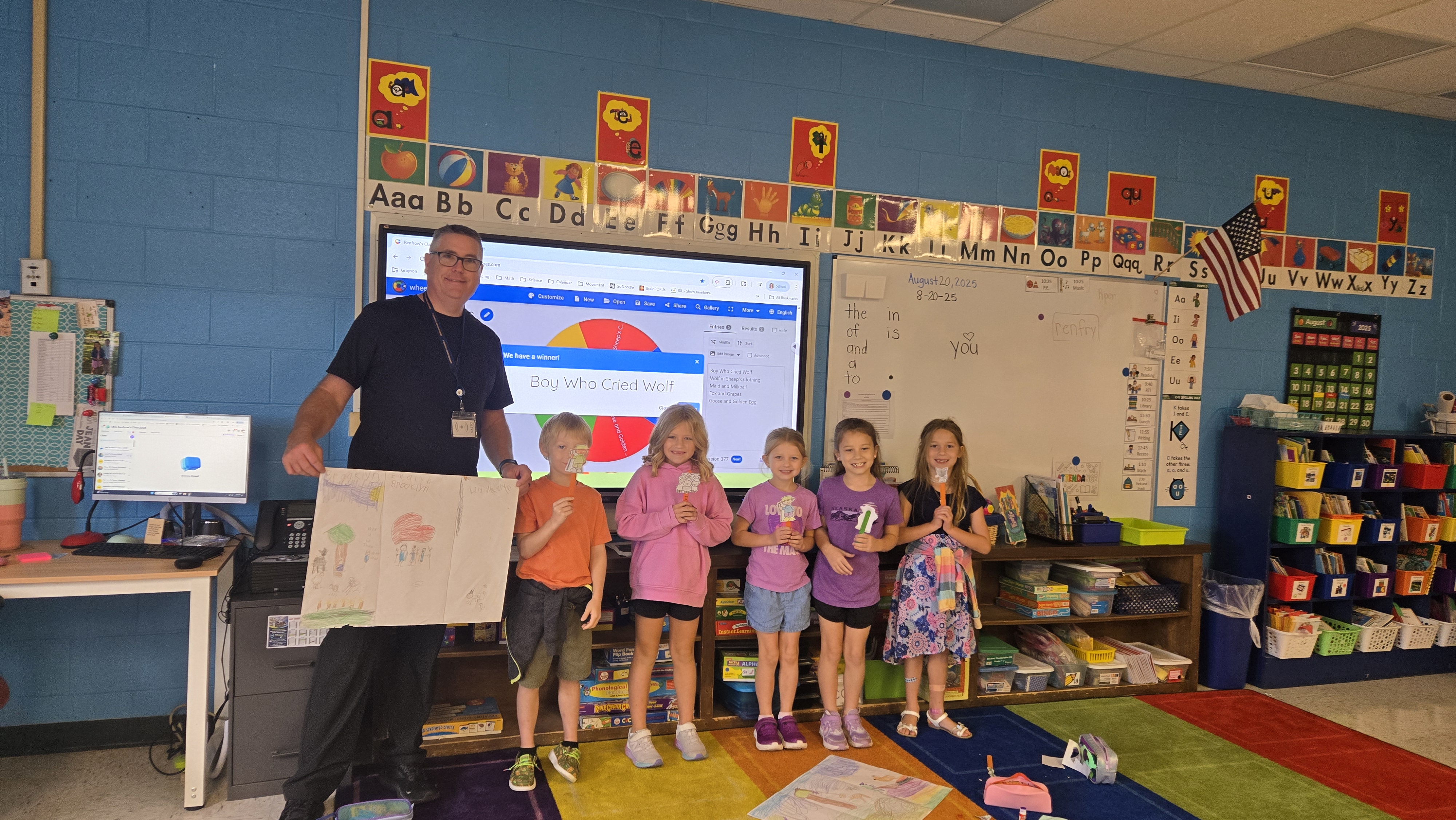 a man and several children in front of a blackboard holding a poster