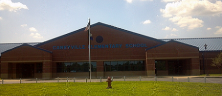 Caneyville School building from front, American flag flies from a pole in center front