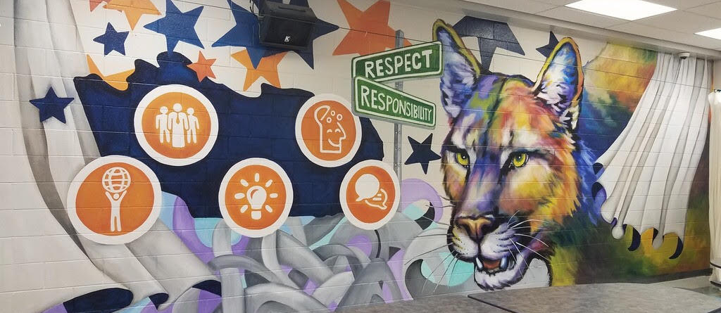 wall mural - round Profile of a Graduate icons on abstract background with orange and blue stars, painted street signs of respect and responsibility, cougar head  behind a lunchroom table