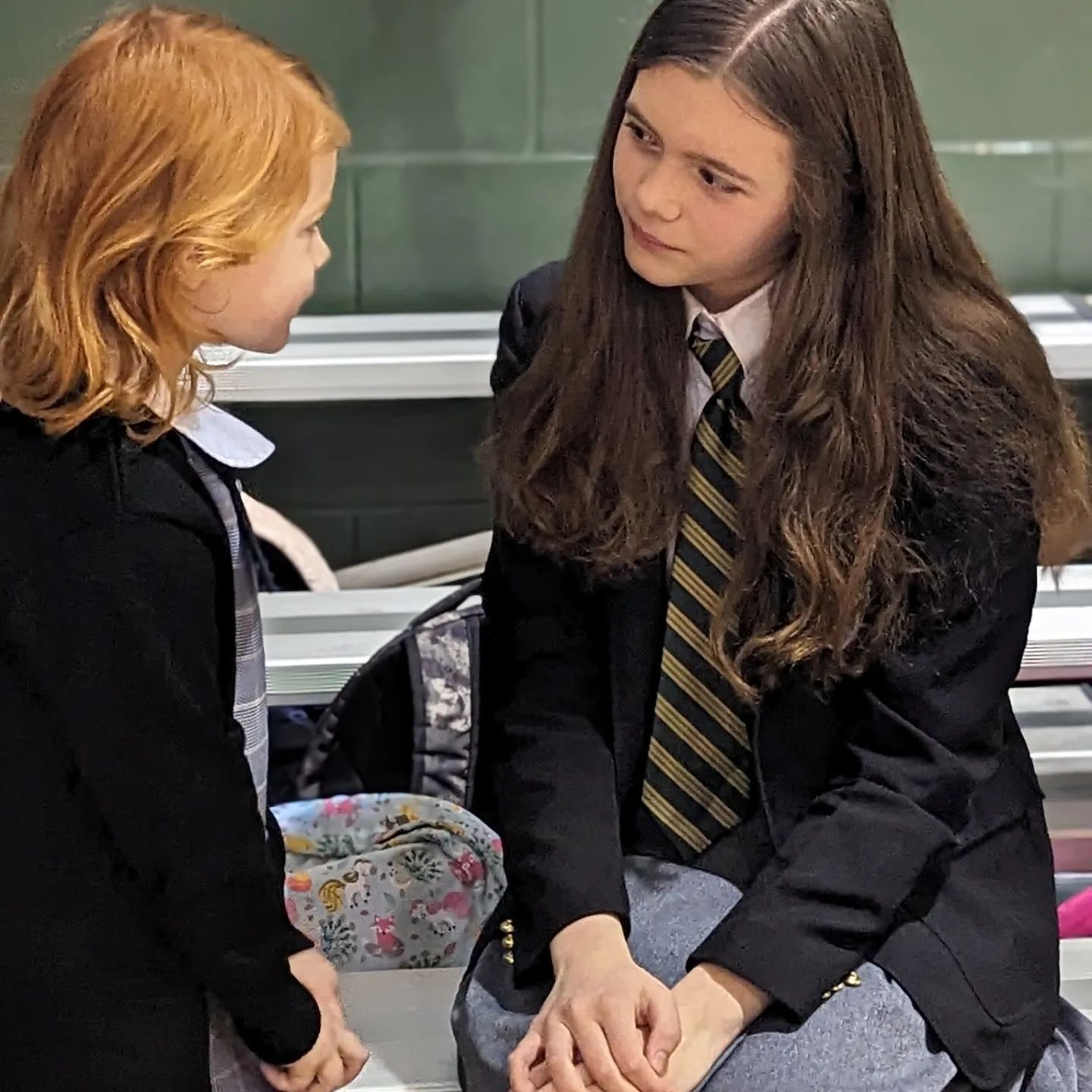 Two students, one in pre-school and one in middle school, having a conversation.