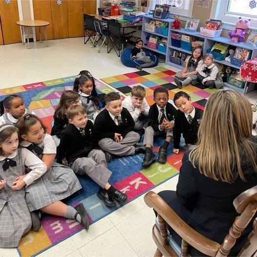 Catholic School Students in gray plaid uniforms being read to by a parent