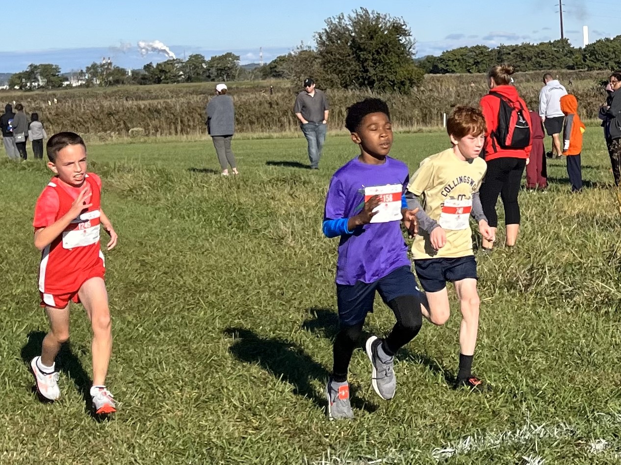 A St. Peter School student runs across the finish line ahead of 2 competitors from other schools