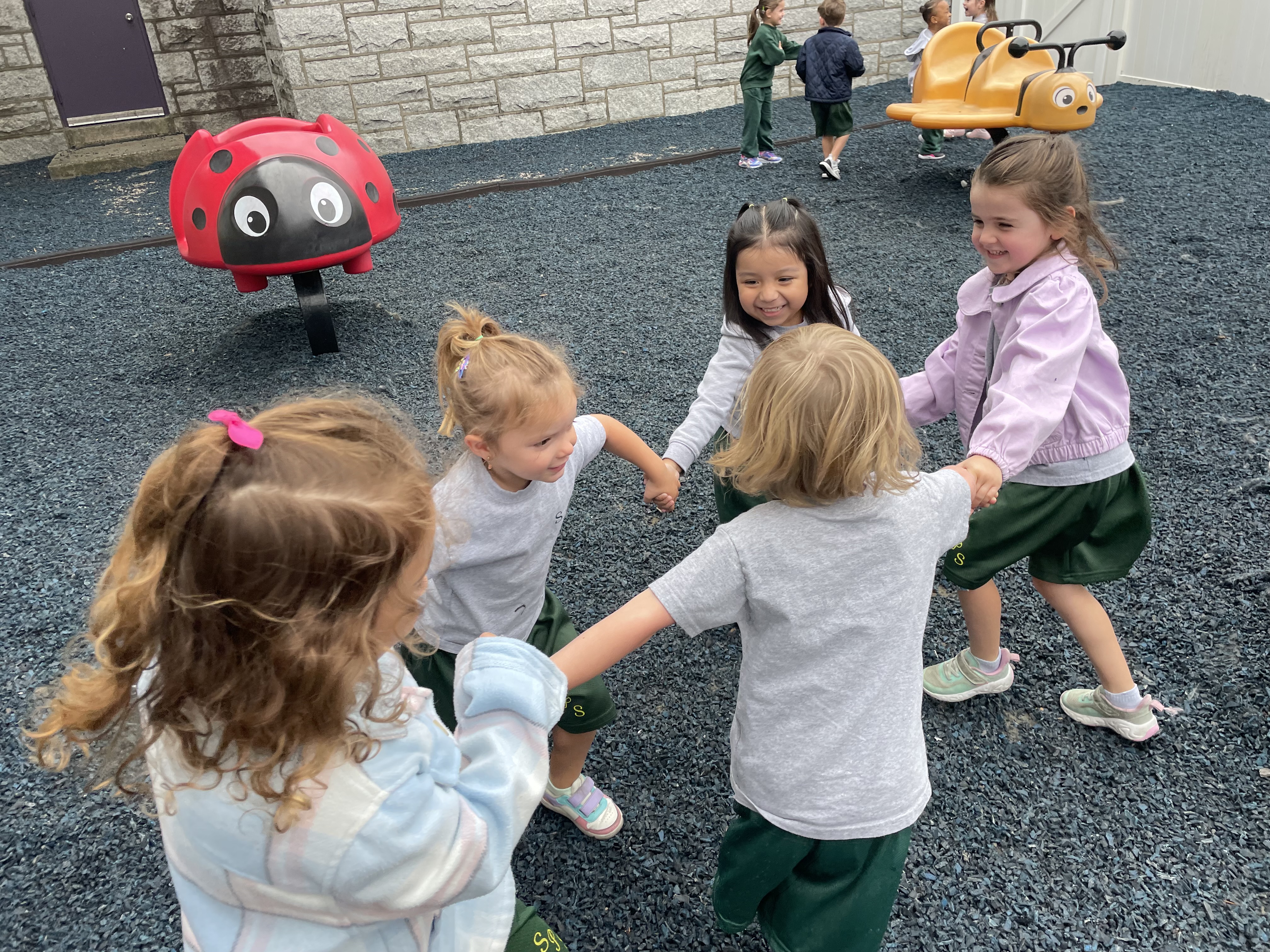 A group of diverse pre-school girls holding hands in a circle