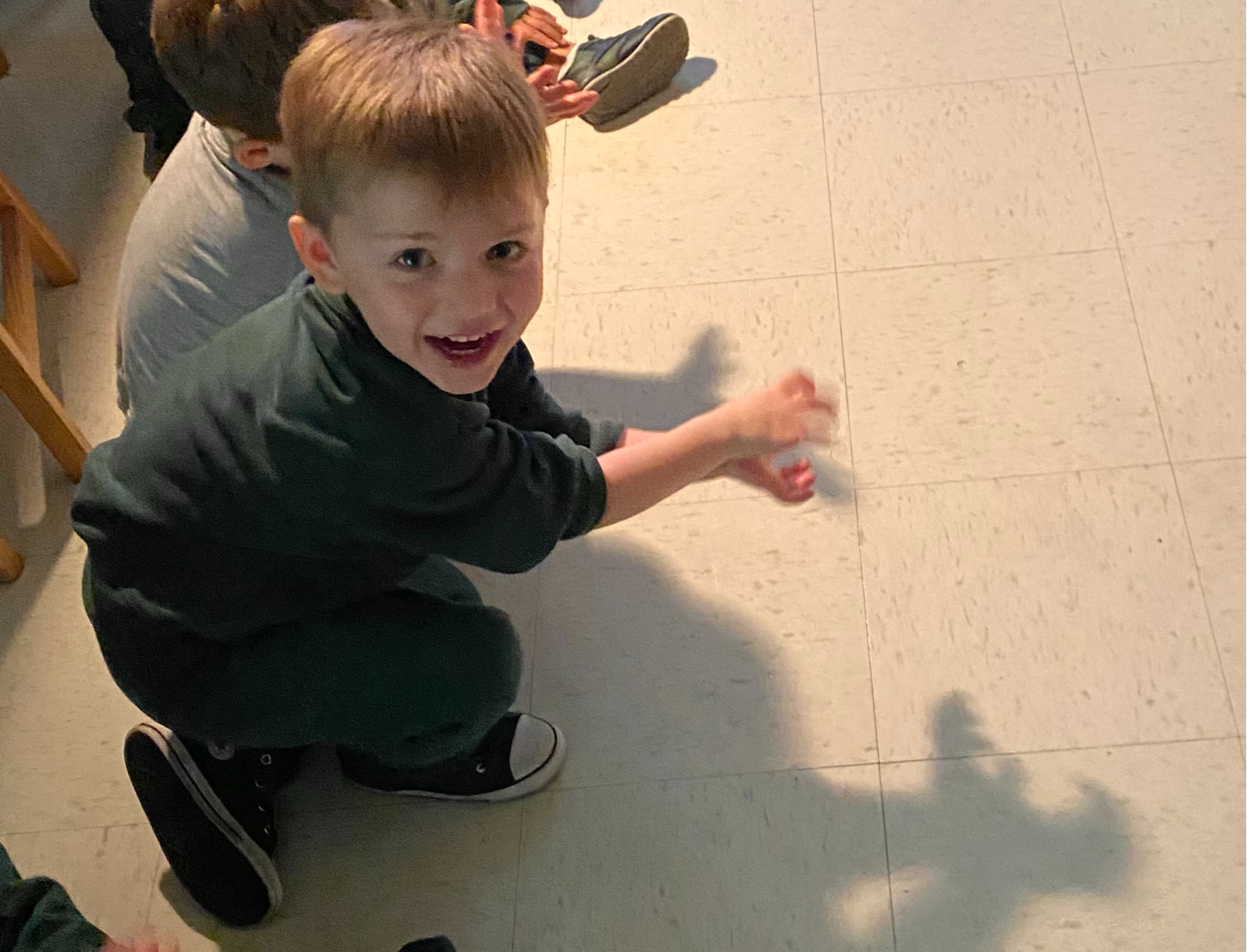 a preschool boy with blond hair making a shadow puppet