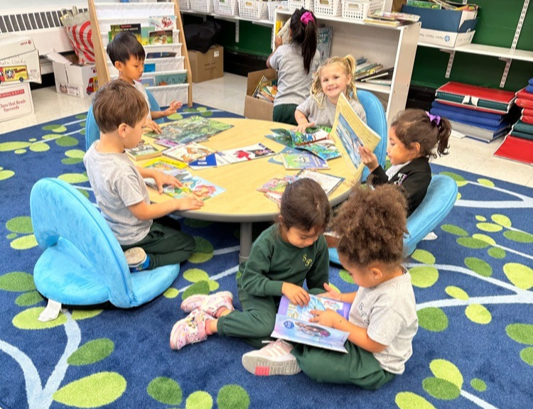 A group of pre-school students reading books on a colorful rug
