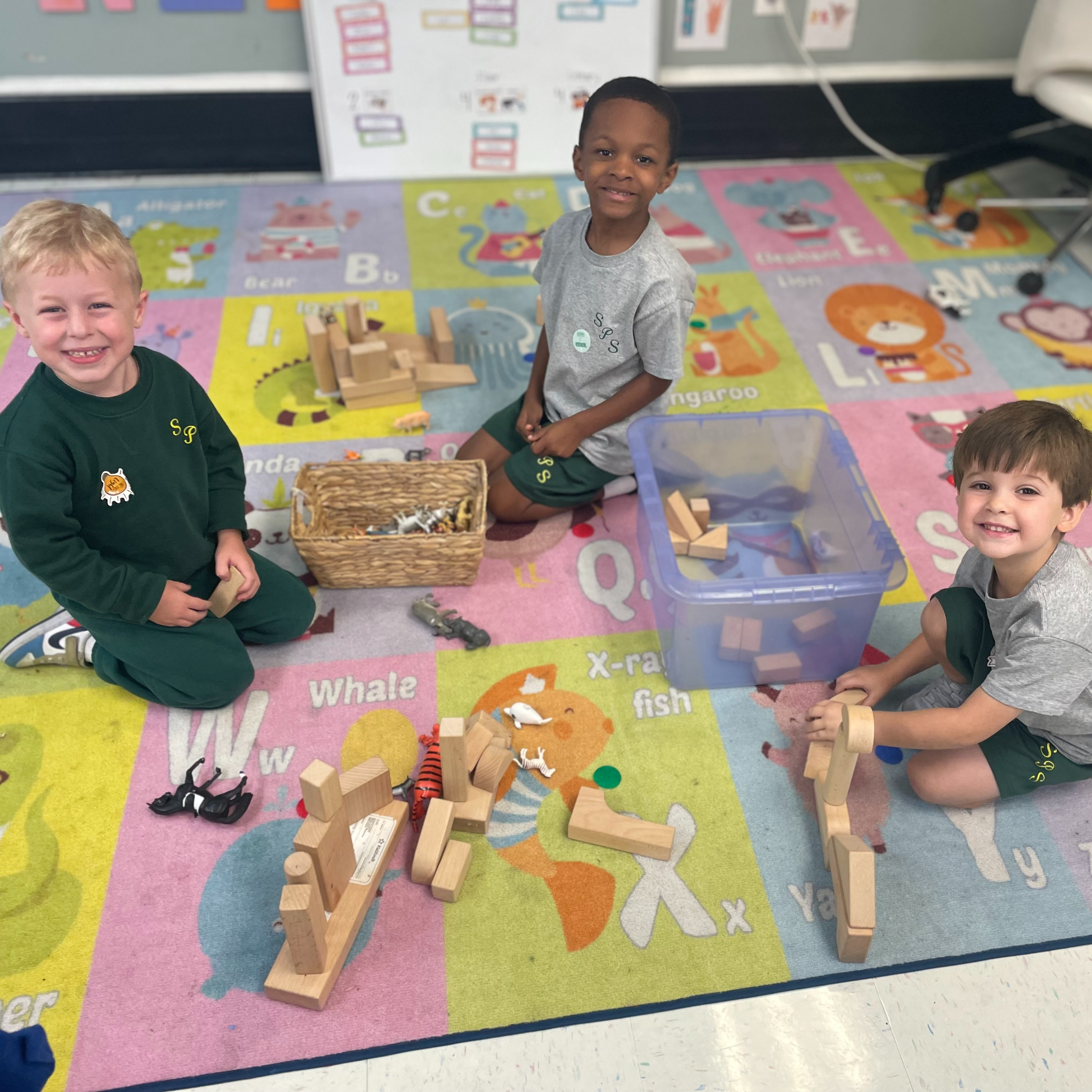Three boys playing with blocks on a colorful pastel carpet