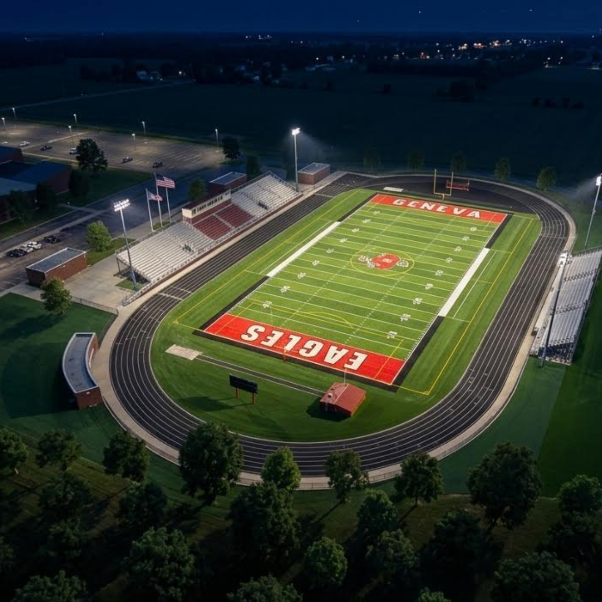 A high-angle view of a football field with large red letters reading "RAVEN" and a track around it.