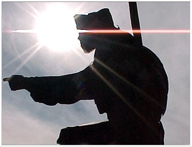 Silhouette of a person or statue against a bright sun
