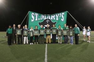 Hall of Fame inductees standing in front of a St. Mary's banner on the football field