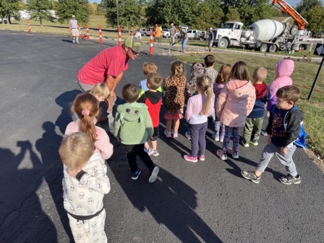 prek students outside looking at concrete work being done
