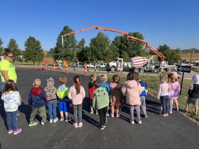 prek students outside looking at concrete work being done