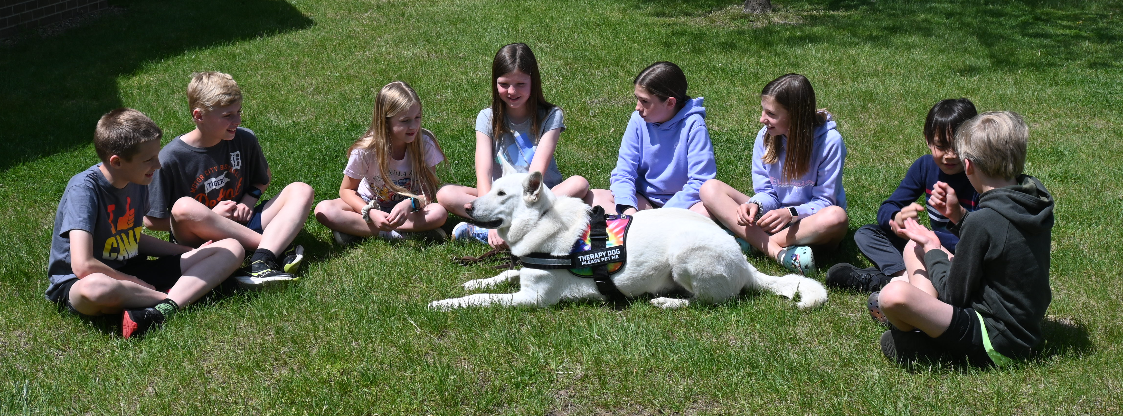 students on playground with therapy dog